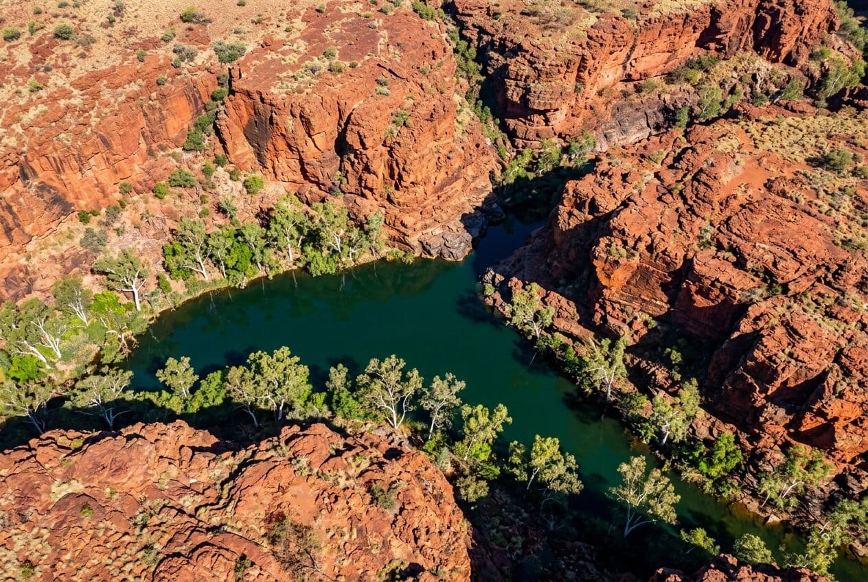 Aerial view of a red rock gorge and waterhole in the Pilbara