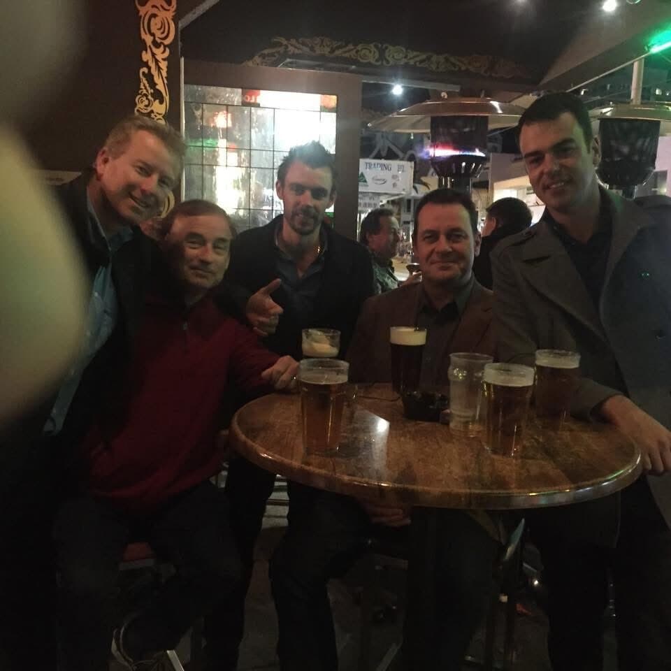 Five men around a bar table with glasses of beer, celebrating the Eco Boss launch at night